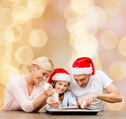 Image showing happy family in santa helper hats cooking