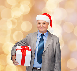 Image showing smiling man in suit and santa helper hat with gift