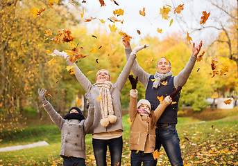 Image showing happy family playing with autumn leaves in park