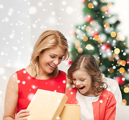 Image showing smiling mother and daughter with gift box at home