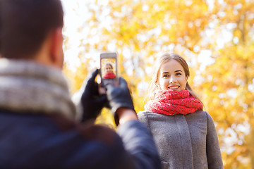 Image showing smiling couple with smartphone in autumn park