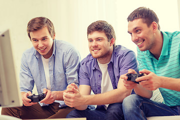 Image showing smiling friends playing video games at home