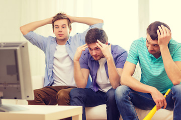 Image showing sad male friends with vuvuzela watching sports