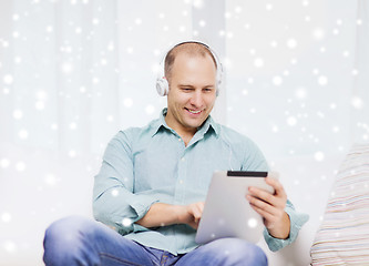 Image showing smiling man with tablet pc sitting on couch