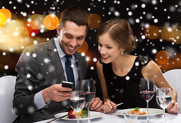 Image showing smiling couple with smartphone at restaurant