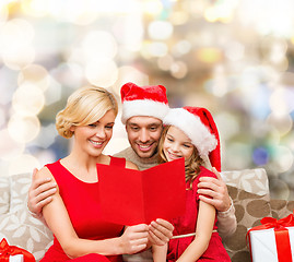 Image showing happy family in santa hats with greeting card