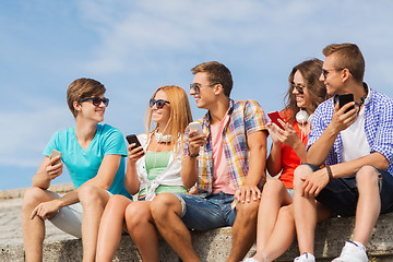 Image showing group of smiling friends with smartphones outdoors