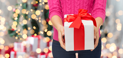 Image showing close up of woman in pink sweater holding gift box