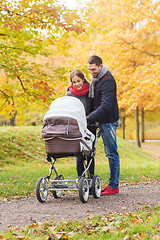 Image showing smiling couple with baby pram in autumn park