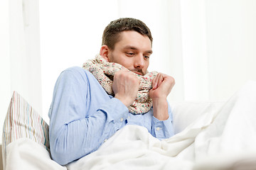 Image showing ill man wearing scarf lying in bed at home