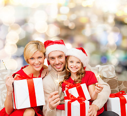 Image showing happy family in santa helper hats with gift boxes