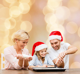 Image showing happy family in santa helper hats cooking