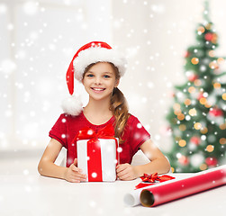 Image showing smiling girl in santa helper hat with gift box