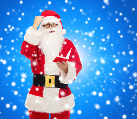 Image showing man in costume of santa claus with notepad