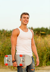 Image showing smiling teenage boy with skateboard outdoors