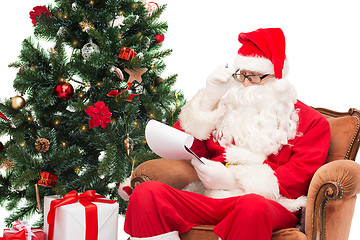 Image showing man in costume of santa claus with notepad