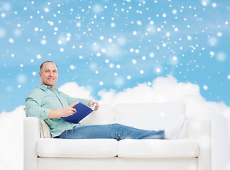 Image showing smiling man with book lying on sofa