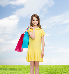 Image showing smiling little girl in dress with shopping bags