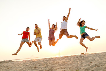 Image showing smiling friends dancing and jumping on beach