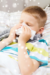 Image showing ill boy blowing nose with tissue at home