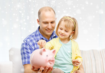 Image showing happy father and daughter with big piggy bank