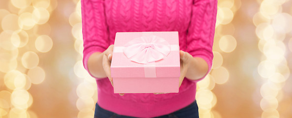 Image showing close up of woman in pink sweater holding gift box