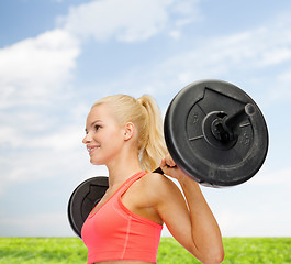 Image showing smiling sporty woman exercising with barbell