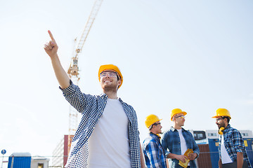 Image showing group of smiling builders in hardhats outdoors