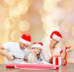 Image showing happy family in santa helper hats packing gift