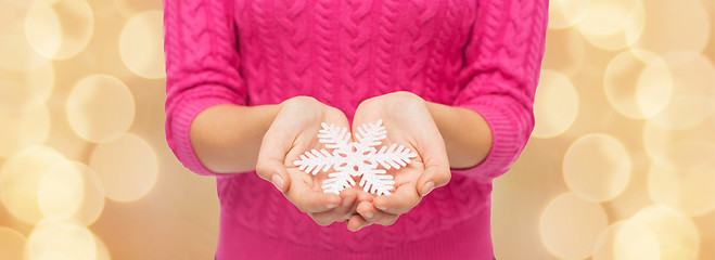 Image showing close up of woman in sweater holding snowflake