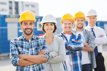 Image showing group of smiling builders in hardhats outdoors