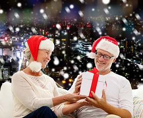 Image showing happy senior couple in santa hats with gift box