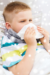 Image showing ill boy blowing nose with tissue at home