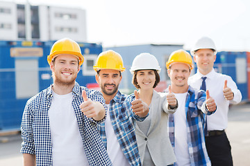 Image showing group of smiling builders in hardhats outdoors