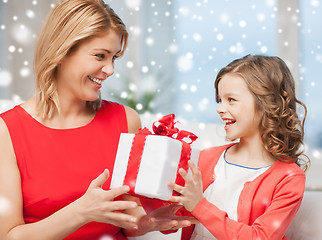 Image showing smiling mother and daughter with gift box at home