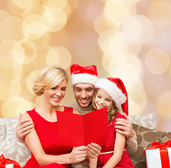 Image showing happy family in santa hats with greeting card