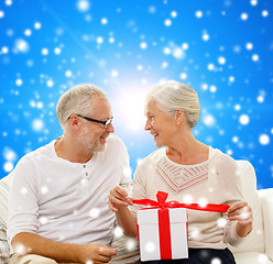 Image showing happy senior couple with gift box at home