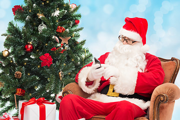 Image showing santa claus with smartphone and christmas tree