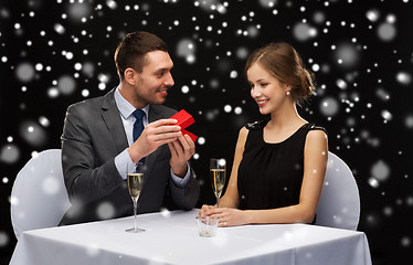 Image showing smiling couple with red gift box at restaurant