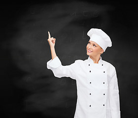 Image showing smiling female chef pointing finger to something