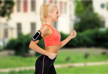 Image showing sporty woman running with smartphone and earphones