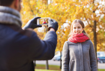 Image showing smiling couple with smartphone in autumn park