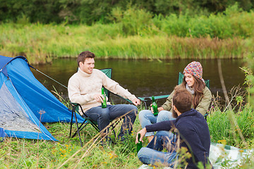 Image showing group of smiling tourists drinking beer in camping