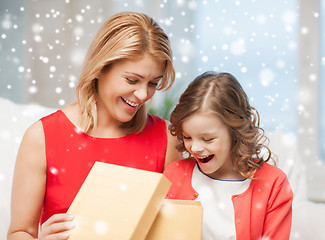 Image showing smiling mother and daughter with gift box at home