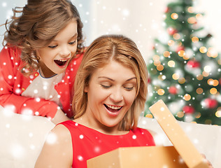 Image showing smiling mother and daughter with gift box at home