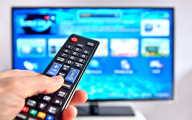 Image showing Smart tv and hand pressing remote control