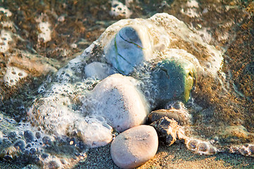 Image showing Small sea stones on the seashore, covered with a sea wave.