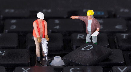 Image showing Miniature workers with drill working on keyboard