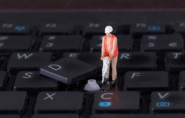 Image showing Miniature worker with drill working on keyboard