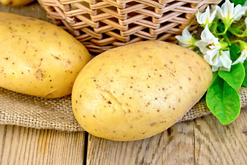 Image showing Potatoes yellow with flower and basket on board